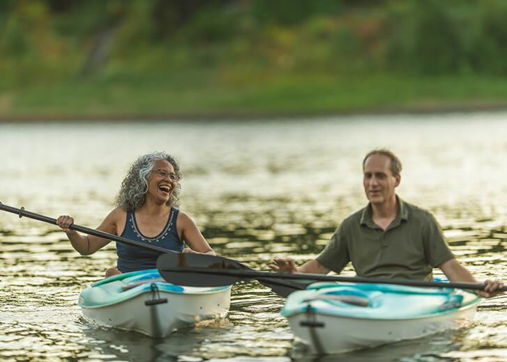 Older mature couple kayaking together during summer